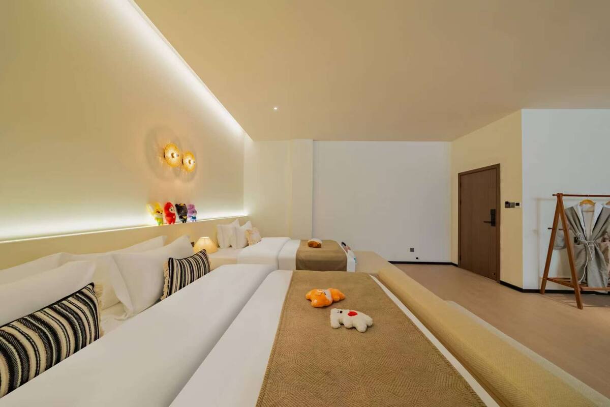Ein Hotelzimmer mit zwei Betten, einer Sitzecke, einer Holztür und einem Kleiderständer.