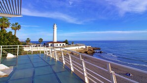 A beach with a white lighthouse, clear blue sky, and calm sea. - Castillo Bajo in Torrox (Torrox)