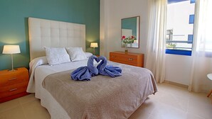 A hotel room with a bed, two bedside tables with lamps, a dresser, a mirror, and a window with curtains. - Castillo Bajo in Torrox (Torrox)