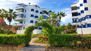 A modern building with multiple balconies and a well-maintained garden with tropical plants and flowers. - Castillo Bajo in Torrox (Torrox)