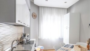 Una cocina moderna con un lavamanos integrado, un reloj en la pared y una zona de comedor con mesa y sillas.