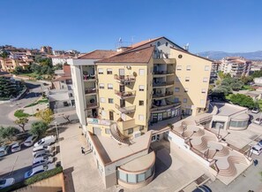 Un immeuble à plusieurs étages doté de balcons, d’un espace de stationnement et offrant une vue dégagée sur le quartier environnant.