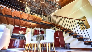 A spacious living area with a wooden staircase, modern furniture, and a unique chandelier. - Atlas Apartments  (Bergamo)