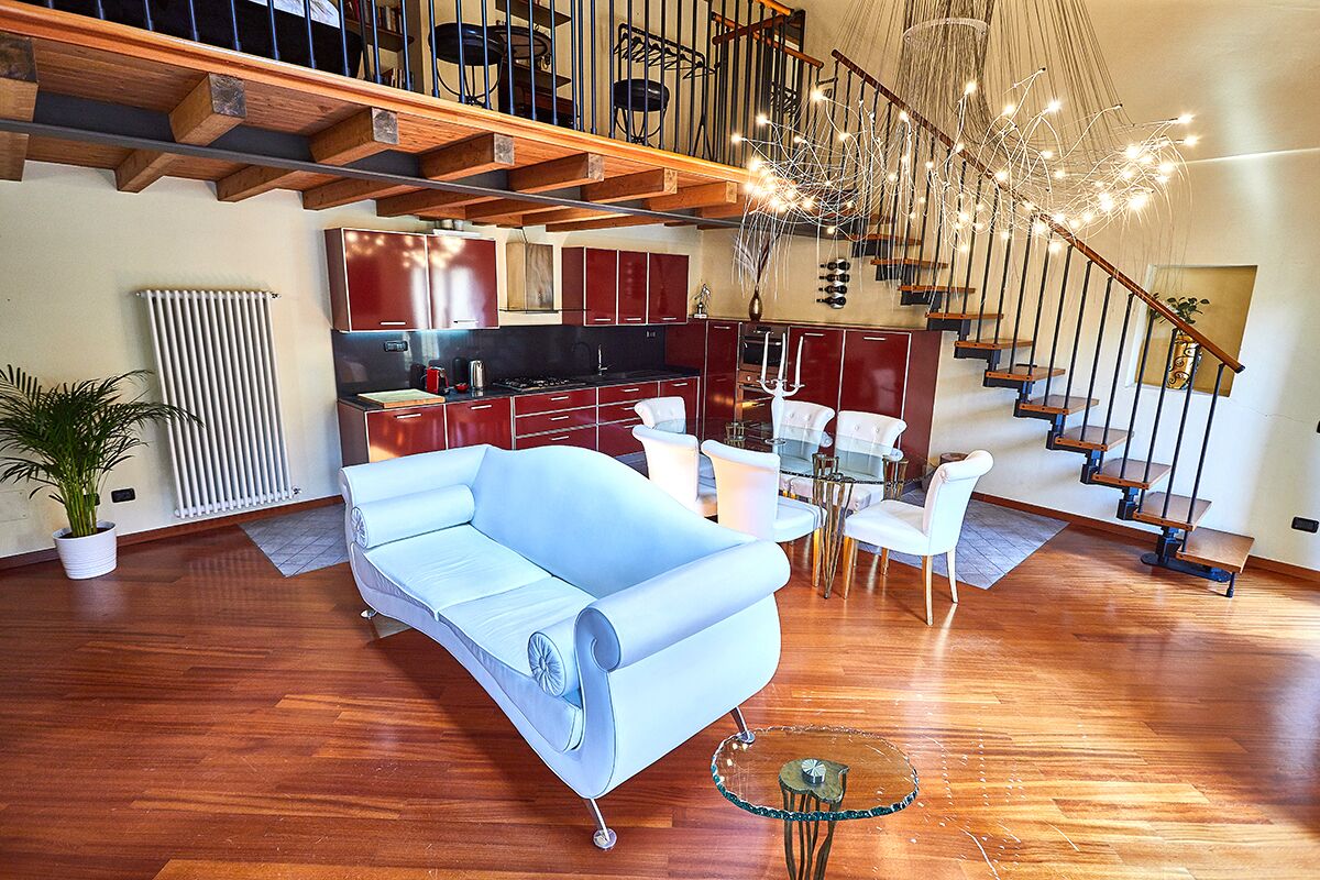 Un amplio salón con un sofá moderno, una mesa de comedor y una escalera que sube a un piso superior.