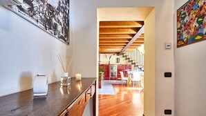 A modern kitchen with wooden beams, a dining area with a table and chairs, and a staircase leading to an upper level. - Atlas Apartments  (Bergamo)