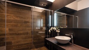 A modern bathroom with a glass shower enclosure, a large sink, and a mirror above it. - Astoria Boutique Apartments (Bologna)