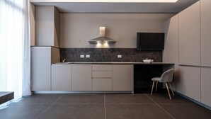 A modern kitchen with a built-in stove, a microwave, and a TV mounted above the counter. - Astoria Boutique Apartments (Bologna)