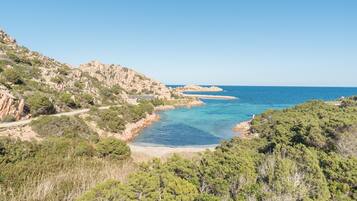 Paesaggio costiero con una strada, terreno roccioso e una spiaggia.