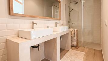 Un baño moderno con dos lavamanos, un espejo grande y una zona de ducha.