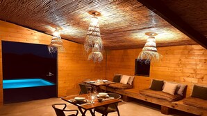 A cozy wooden interior with a dining area, a sofa, and a small pool. - Mimosa Lodge (Quart)