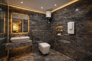 Ein modernes Badezimmer mit Marmorwand, Waschbecken, Toilette und Dusche.
