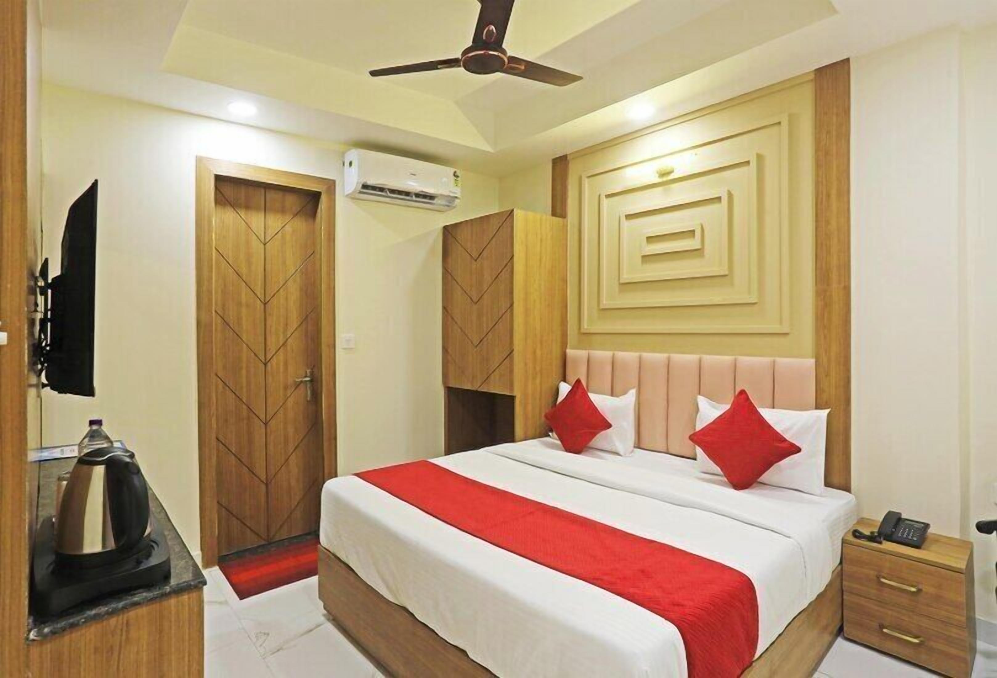 A hotel room with a bed, a TV, a coffee maker, and a telephone.
