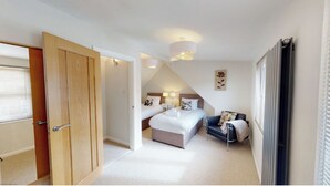 Une chambre avec deux lits, un coin salon et une porte donnant sur une autre pièce.