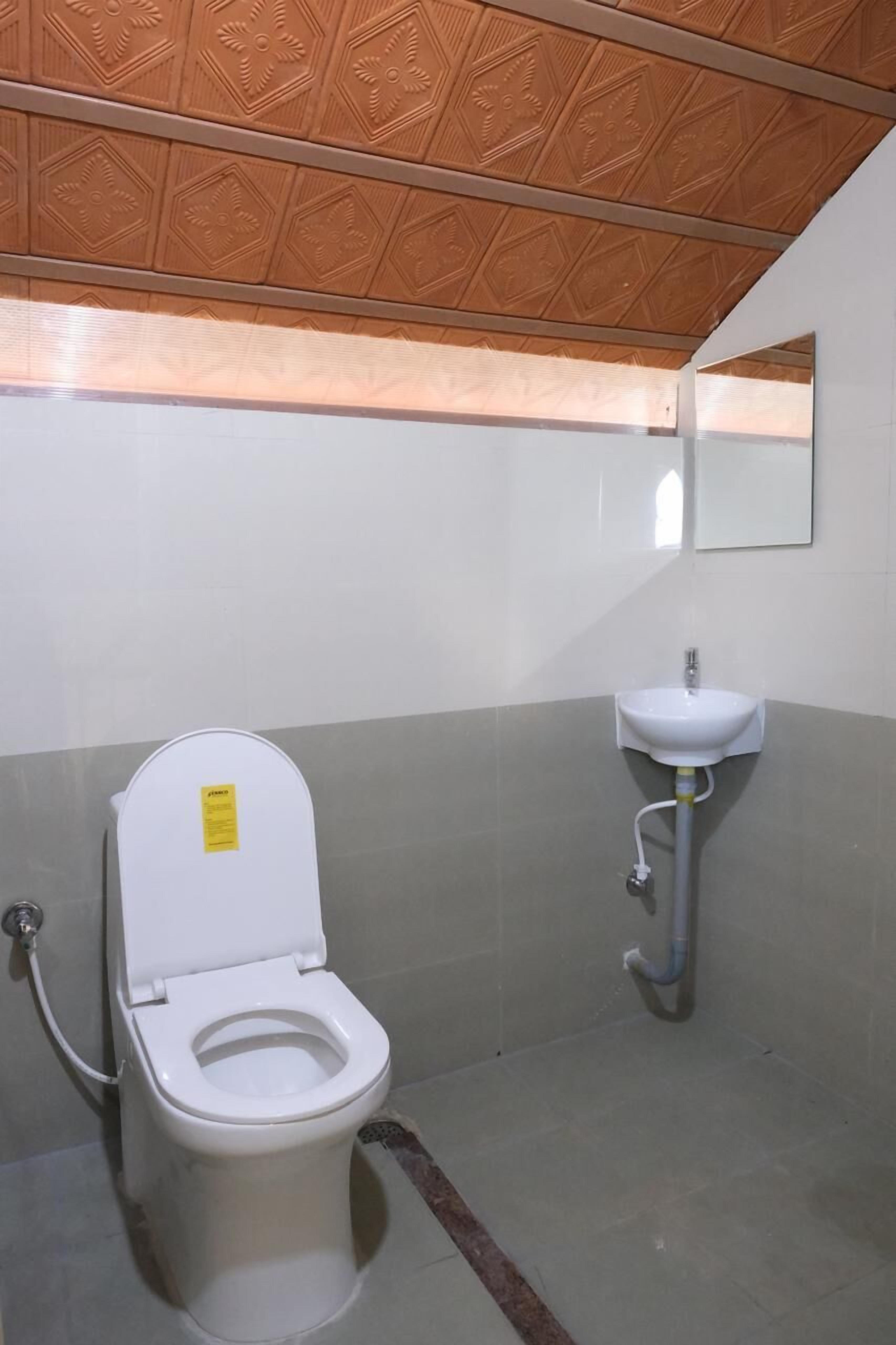 Un baño pequeño con inodoro, lavabo y espejo en la pared.