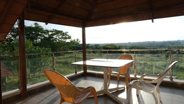 Un espace extérieur abrité, avec une table et des chaises, offrant une vue sur un paysage verdoyant.