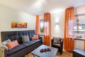 Ein möbliertes Wohnzimmer mit einer Couch, Sesseln, einem Couchtisch und einem Bild von Hirschen.