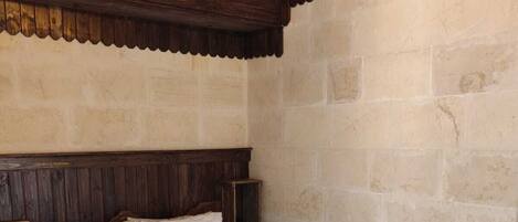 Quarto com cabeceira de madeira, cama com roupa de cama branca e piso de madeira.