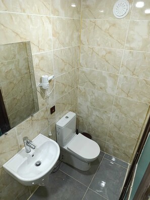 Standaard kamer | Badkamer | Een douche, een haardroger, handdoeken, zeep