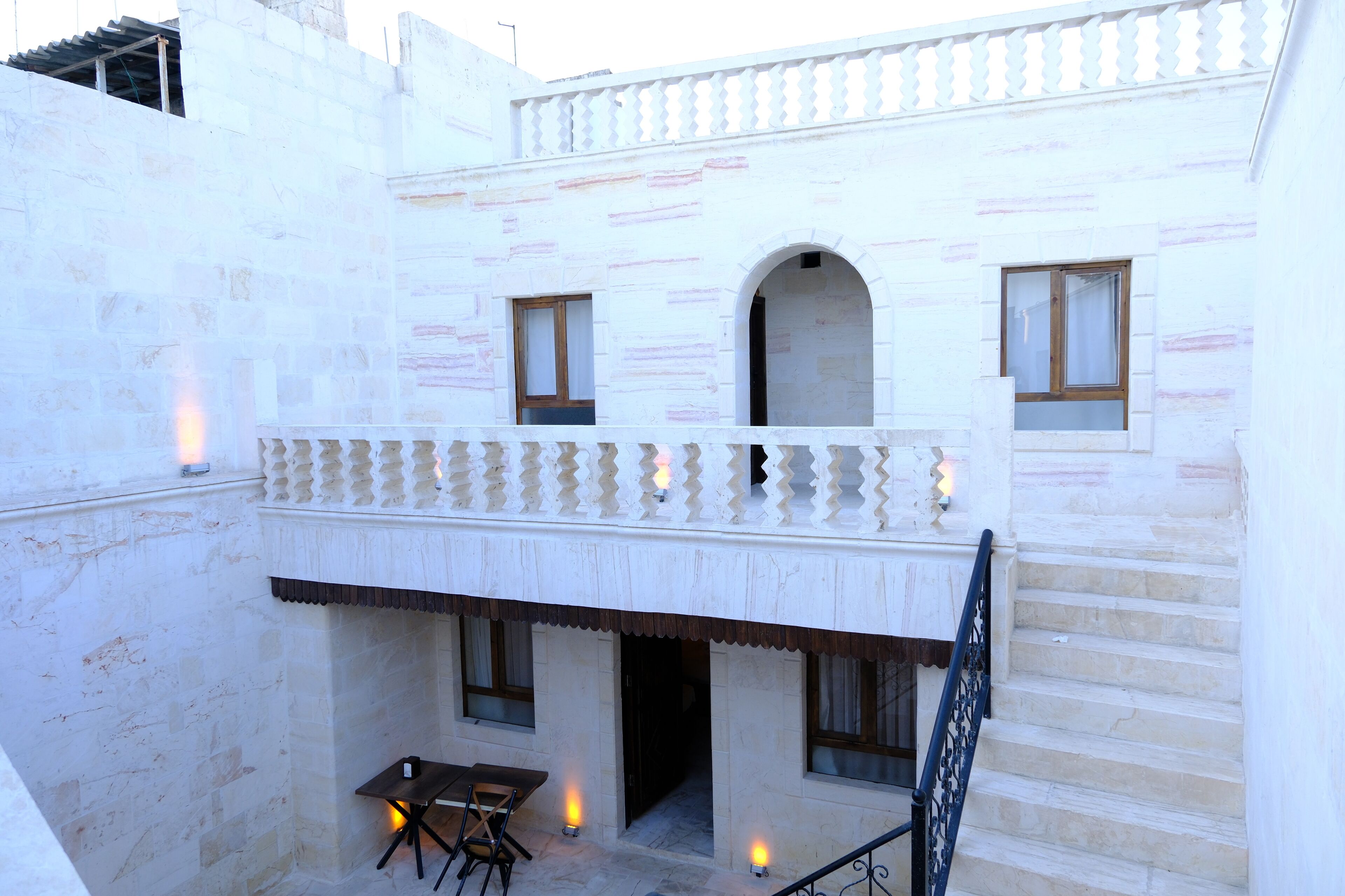 Ein Innenhof mit einer Treppe zu einem Balkon, einem Tisch und Stühlen sowie einem kleinen Fenster.