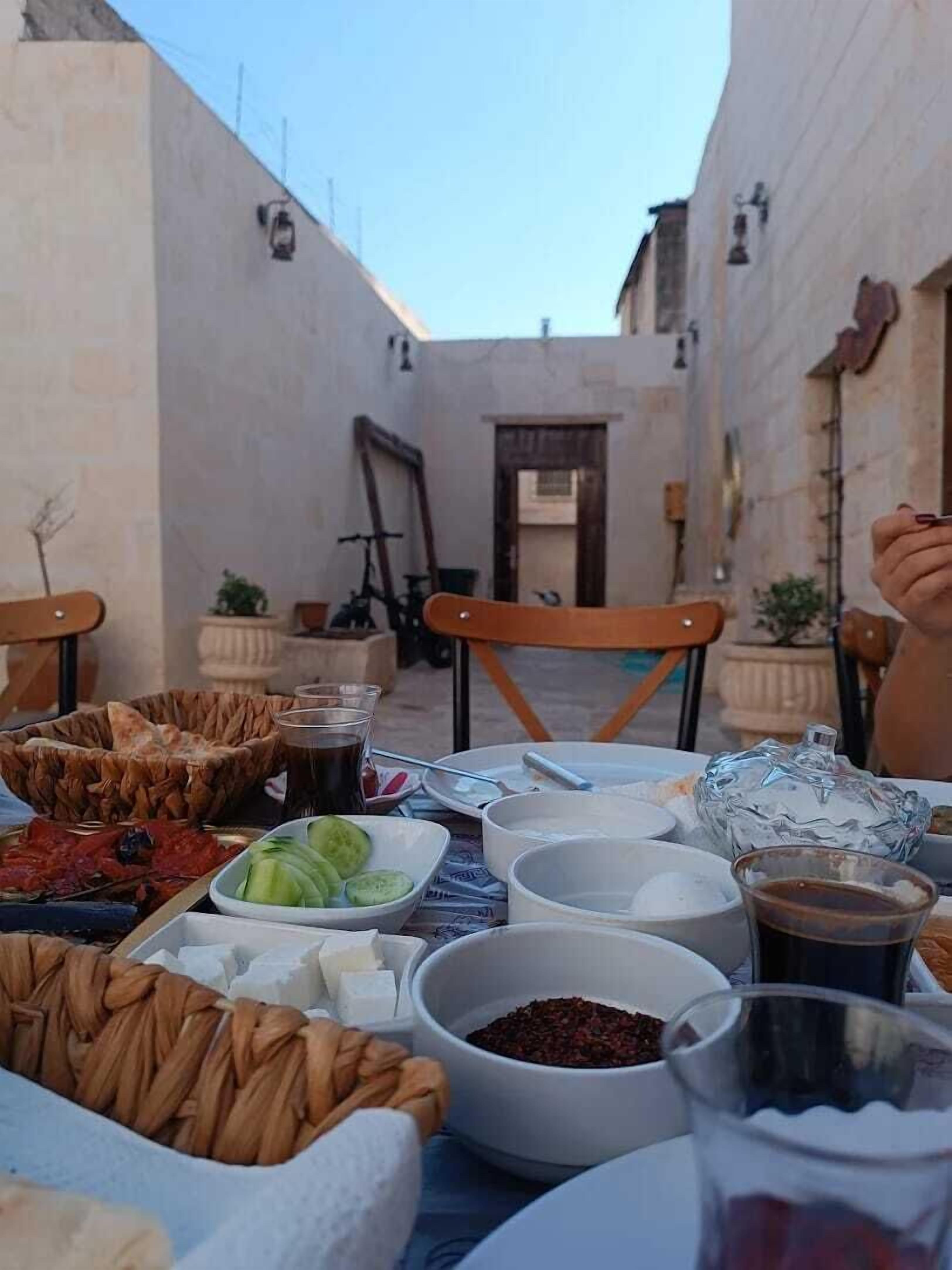 An outdoor dining area with a table set for a meal, including various dishes and drinks.
