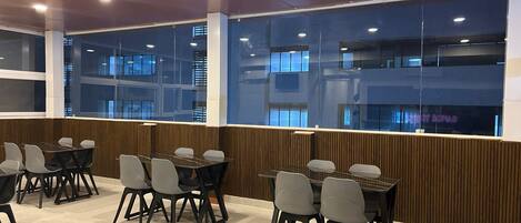 Une salle de conférence moderne avec des murs en verre, plusieurs tables et des chaises.