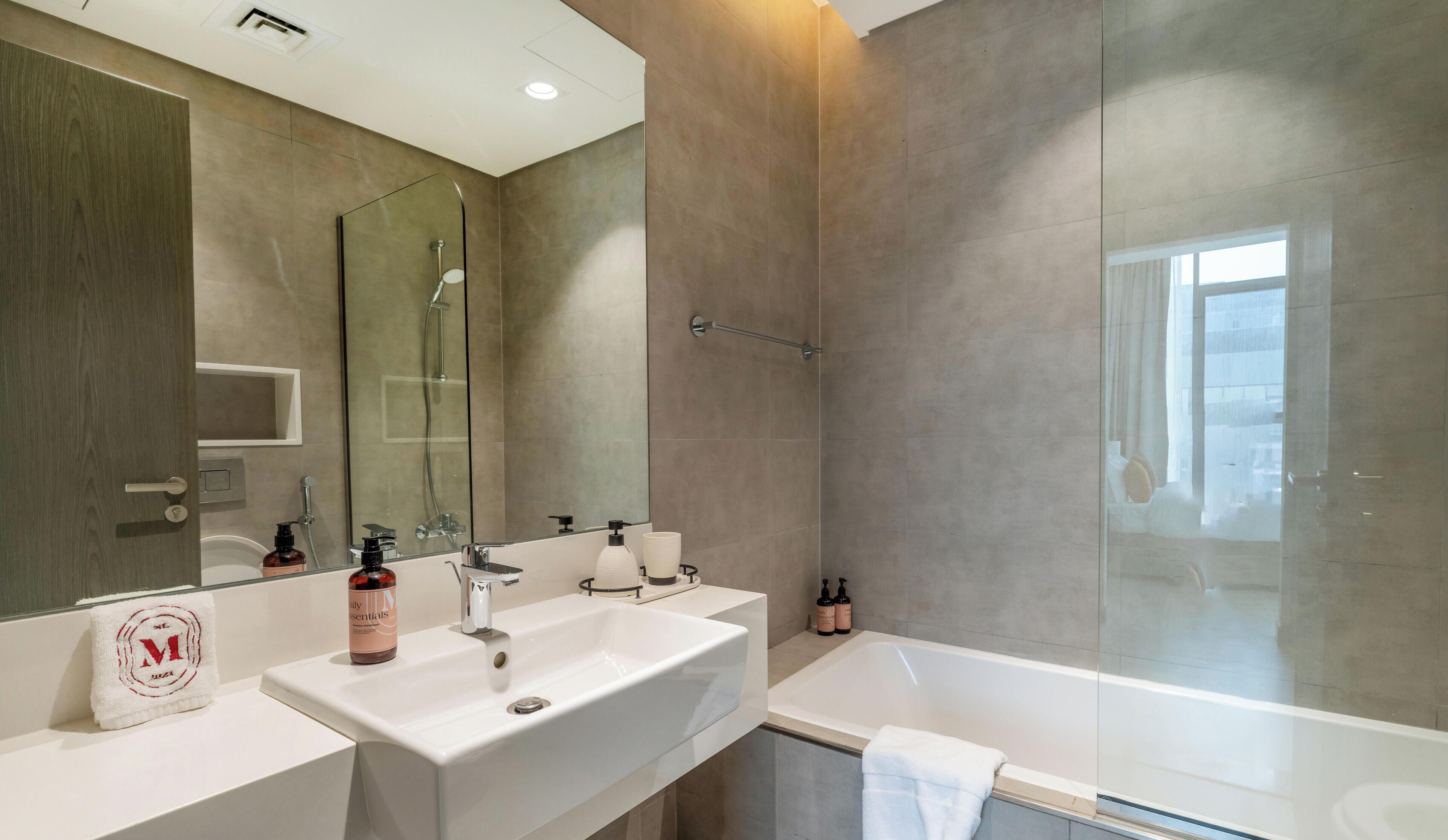 A modern bathroom with a large mirror, two sinks, a shower, and a bathtub.