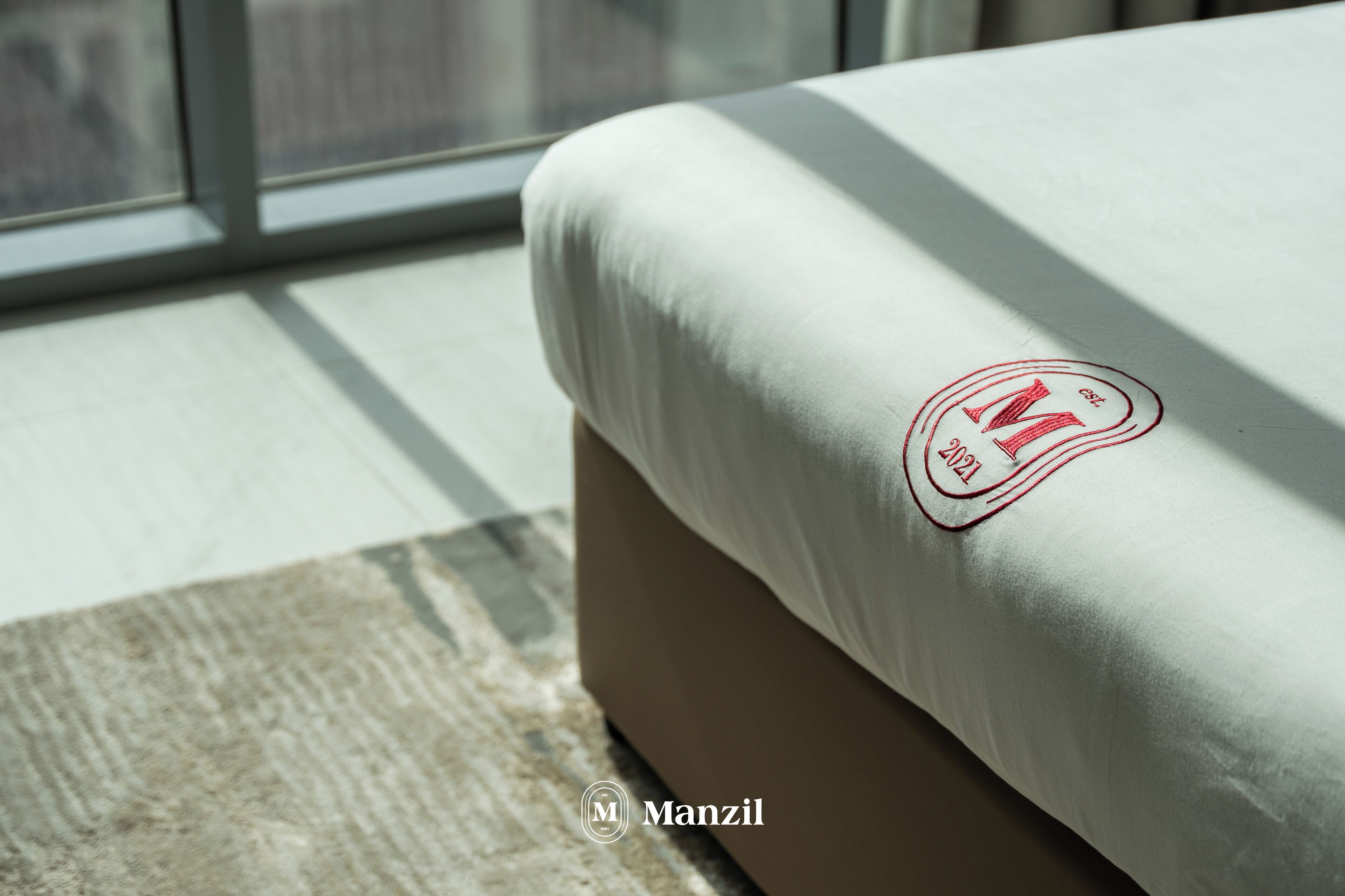 Un lit avec un drap blanc orné d’un logo rouge et de l’année 2021.