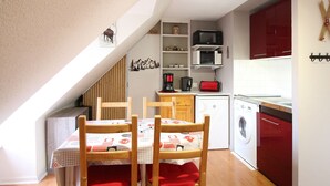 Ett kompakt kök med ett matbord, stolar, en mikrovågsugn och en tvättmaskin.