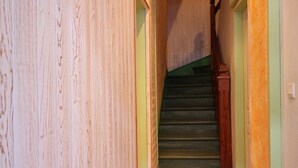 Ein schmaler Korridor mit Holzwänden und einer Treppe, die zu einer zweiten Etage führt.