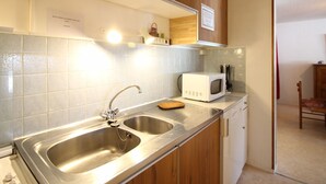 Cozinha com pias de aço inoxidável, micro-ondas e armários de madeira.