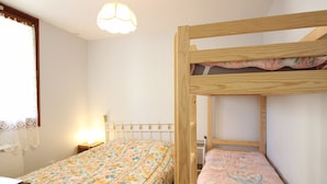 Een slaapkamer met een stapelbed, een bloemenprint sprei, een nachtkastje en een hanglamp.