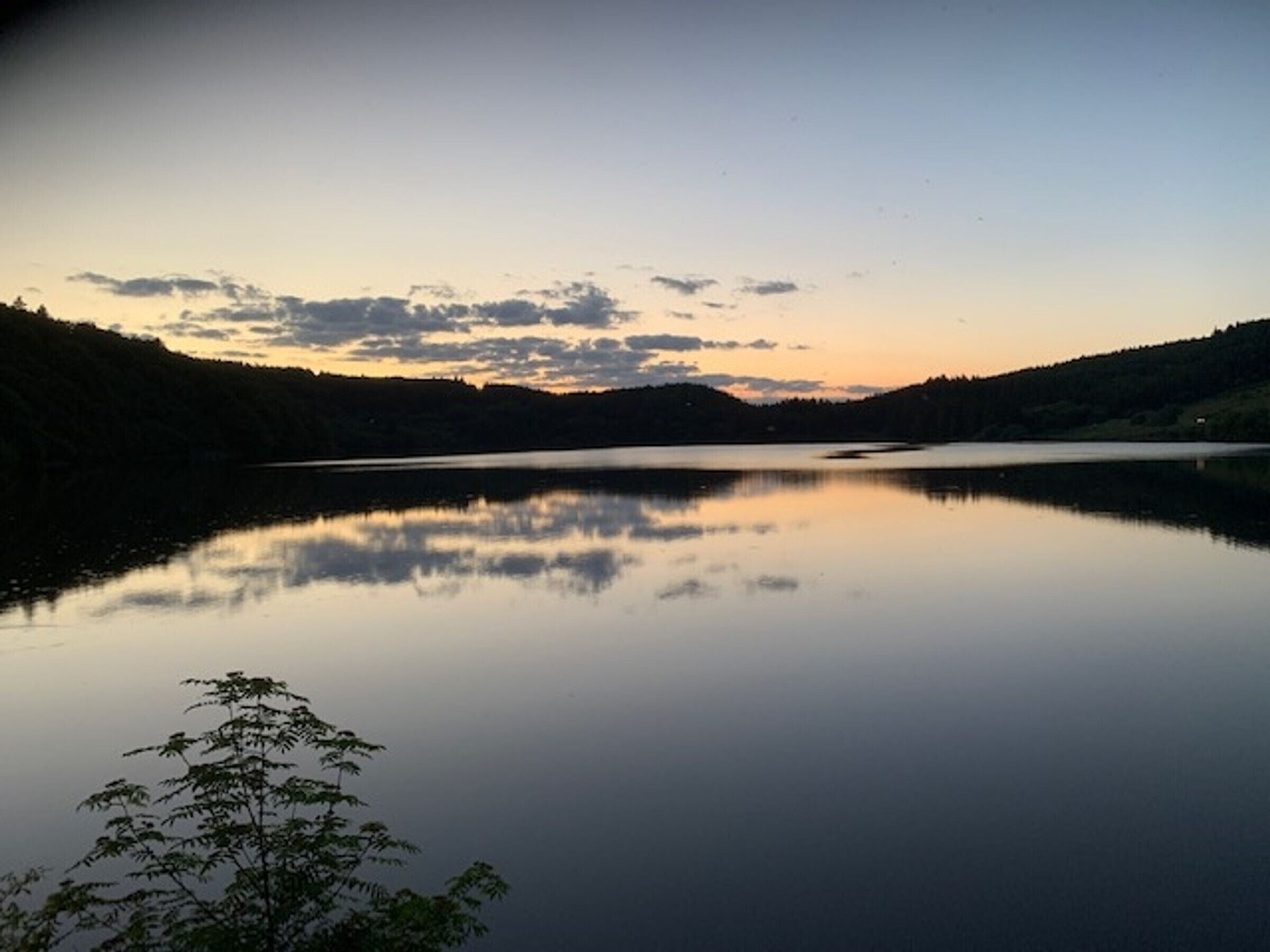 En rolig sø med et klart spejlbillede af himlen og de omkringliggende bakker.