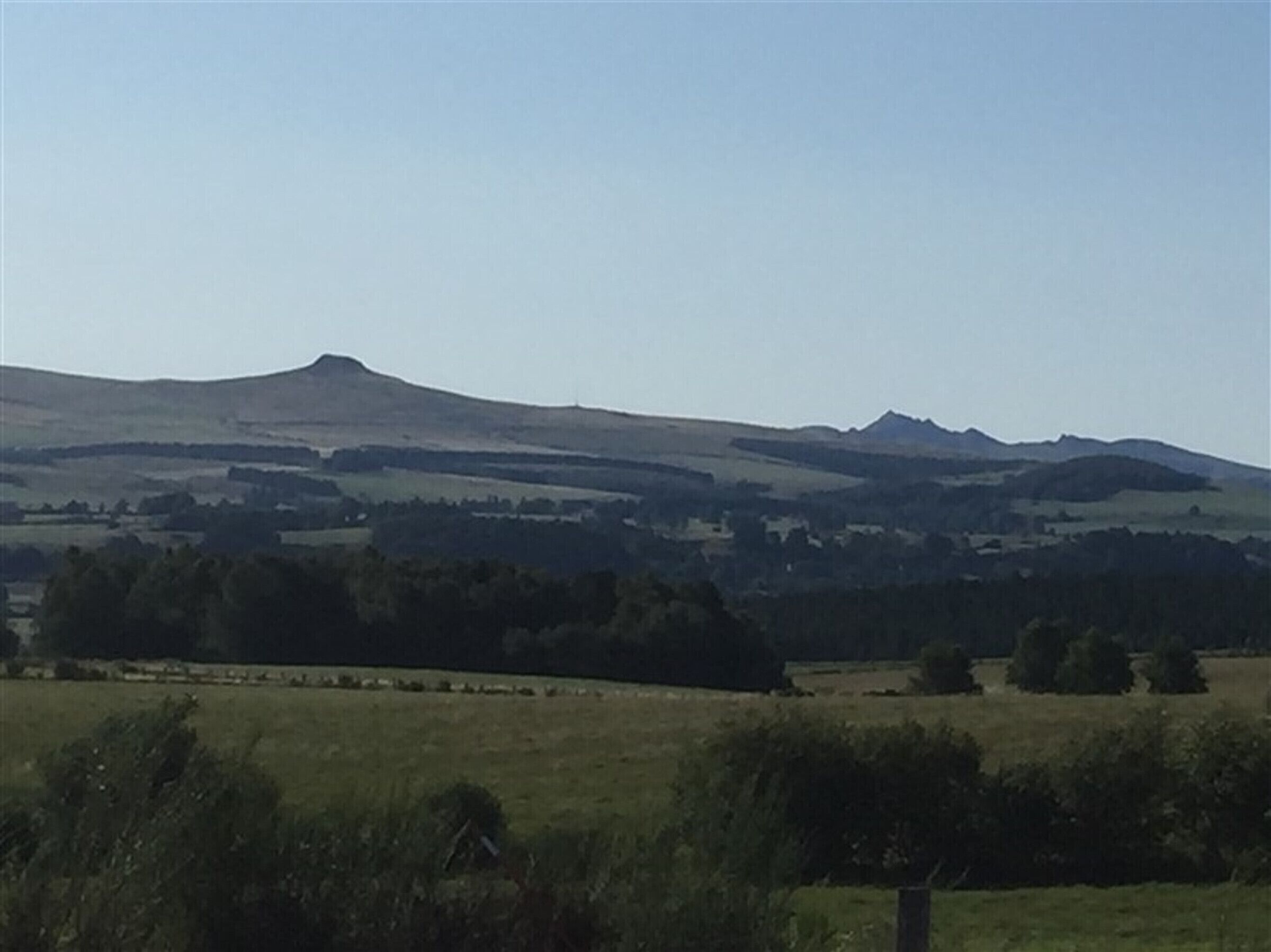 A rural landscape with rolling hills and a clear sky.