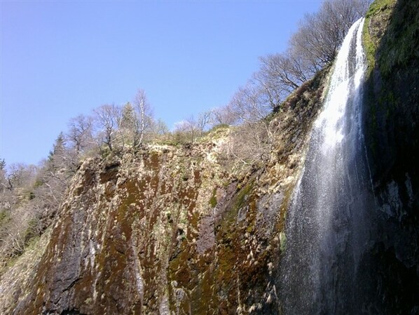A waterfall cascading down a rocky cliff with sparse vegetation. - F2 with WIFI downtown near spa (Mont-Dore)