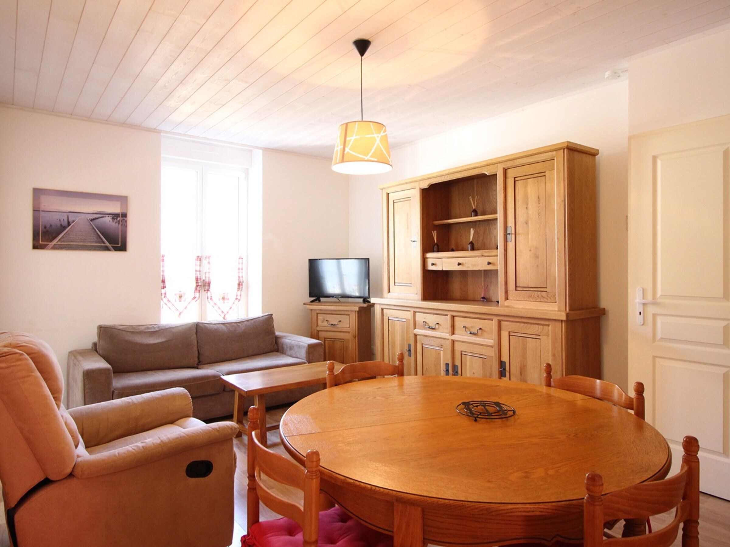 Una sala acogedora con una mesa redonda de madera, un sofá y una televisión.