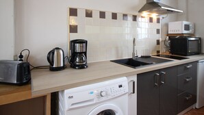 Eine Küche mit Waschmaschine, Kaffeemaschine, Toaster, Mikrowelle und Spüle.