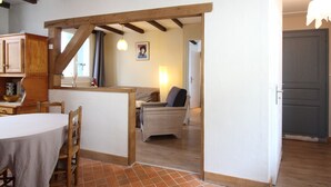 Ein Zimmer mit Holzboden, einem Esstisch mit Stühlen, einem Sofa und einem Bett.