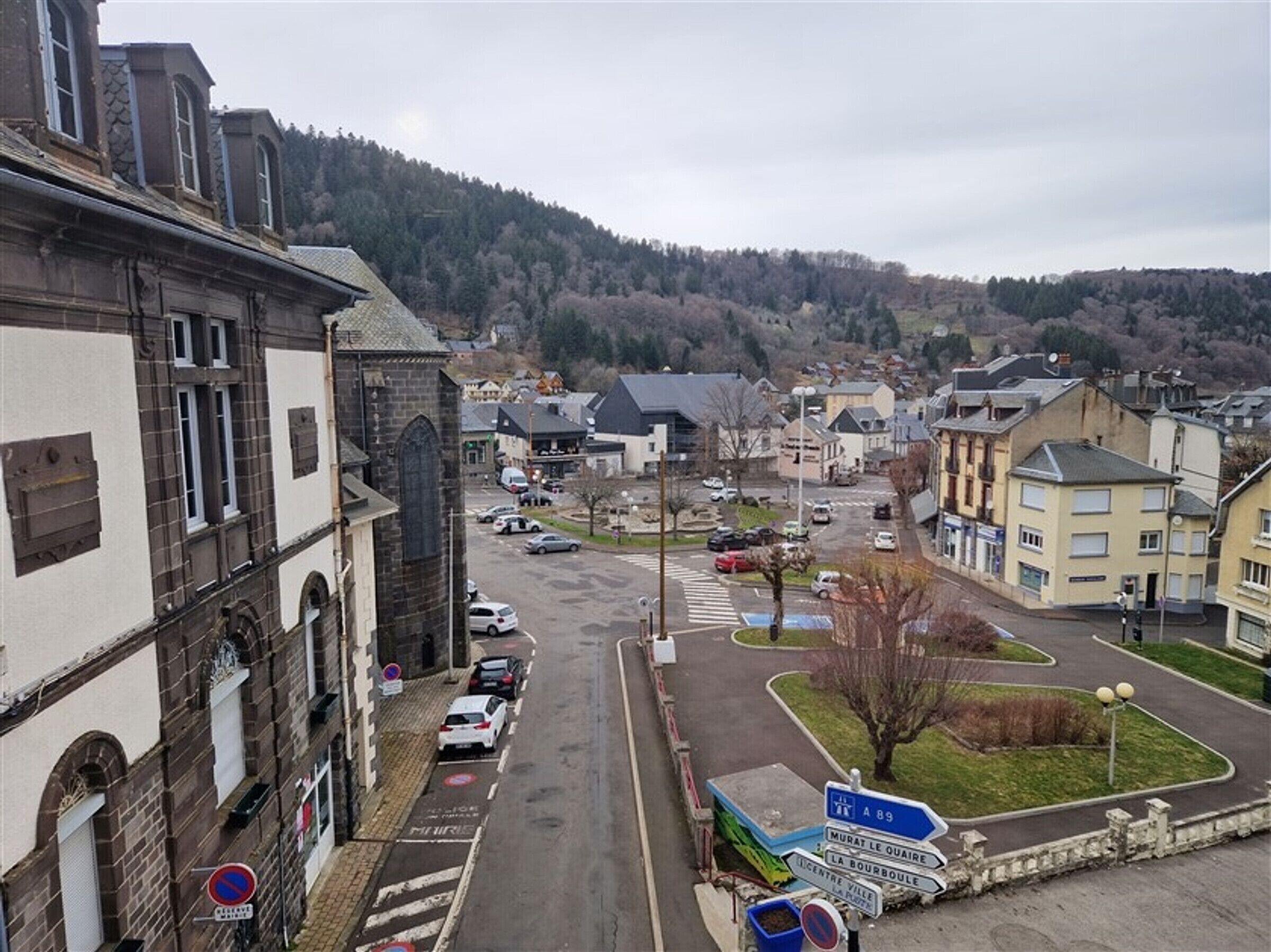 Eine Stadt mit einem markanten Kirchturm, einem Parkplatz und Hinweisschildern.