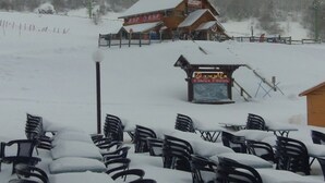 A snow-covered outdoor seating area with a wooden building in the background. - Studio at Mont-Dore slopes, 4 pers. (Mont-Dore)