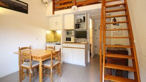 A compact kitchen with a dining area, a wooden staircase, and a small living space. - Studio at Mont-Dore slopes, 4 pers. (Mont-Dore)