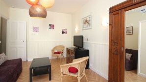 A living room with a sofa, a chair, a table, a television, and a cabinet. - F2 Apartment with terrace and garden, near Mont-Dore center (Mont-Dore)
