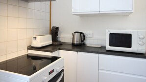 A compact kitchen with a microwave, toaster, kettle, and a built-in oven. - F2 Apartment with terrace and garden, near Mont-Dore center (Mont-Dore)