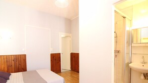 A bedroom with a bed, wooden headboard, and a bathroom with a shower and sink. - F2 Apartment with terrace and garden, near Mont-Dore center (Mont-Dore)