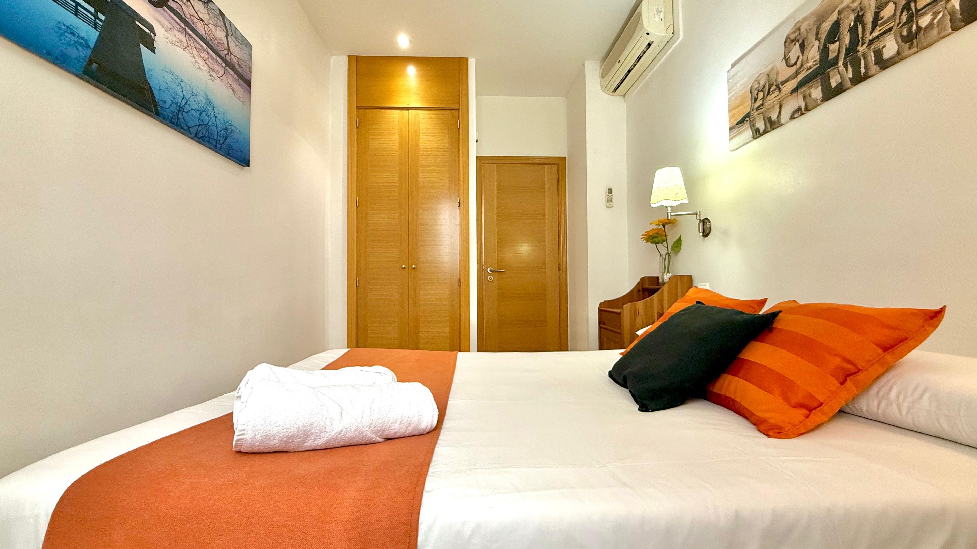 Ein Hotelzimmer mit einem Bett, einem Holzschrank, einem Nachttisch mit Lampe und einem Bild an der Wand.
