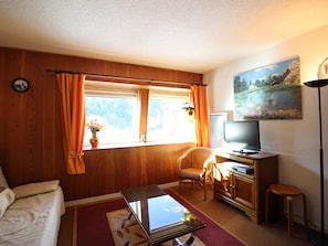 A cozy living room with a sofa, a glass coffee table, a television, and a painting on the wall. - F2 Apartment at the slopes, 6 sleeps, Mont-Dore (Mont-Dore)