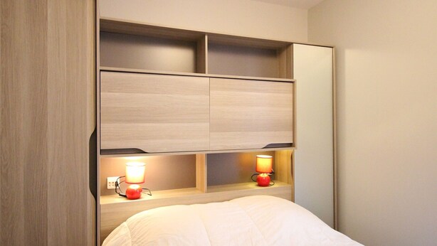Ein Hotelzimmer mit Bett, Nachttisch, Lampe und integriertem Regal.