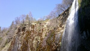 Una cascada se precipita por un risco rocoso con poca vegetación.