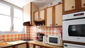 Una cocina con armarios de madera, microondas, horno y cafetera.