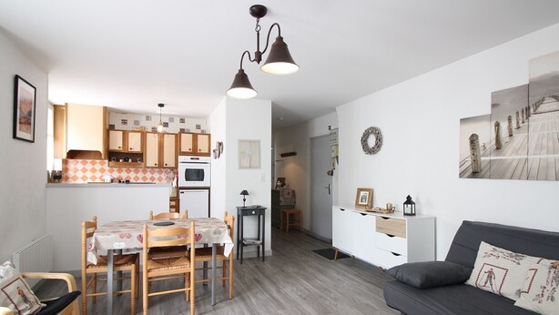 Un espacio habitable compacto con comedor, kitchenette y sofá.
