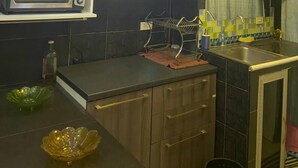 Una cocina moderna con armarios de madera oscura, microondas integrado, pileta de acero inoxidable y lámparas colgantes.